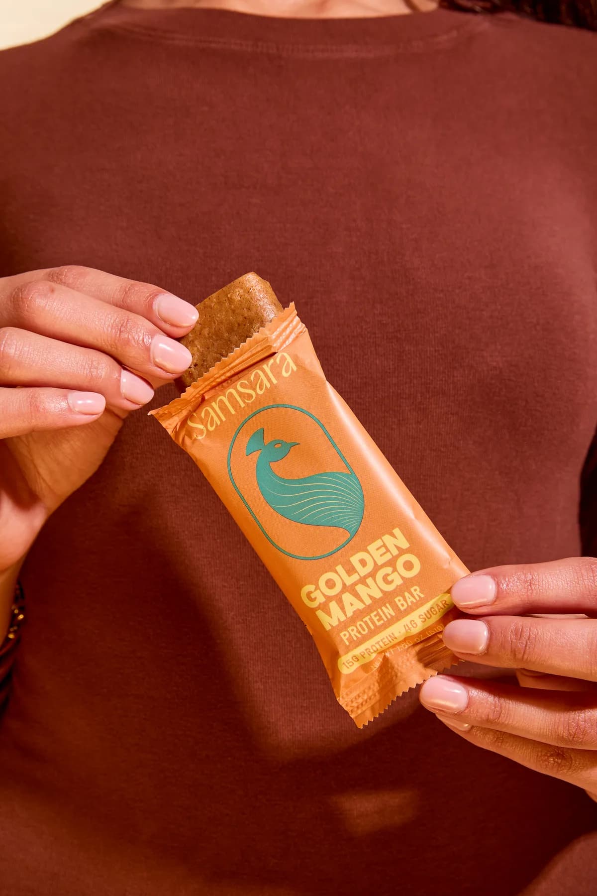 Hands holding a Golden Mango protein bar